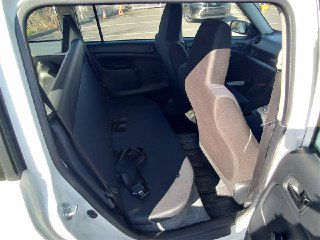 Задние сиденья и пространство для пассажиров Toyota Probox 2018; видно состояние обивки и ремни безопасности на фоне дневной стоянки.