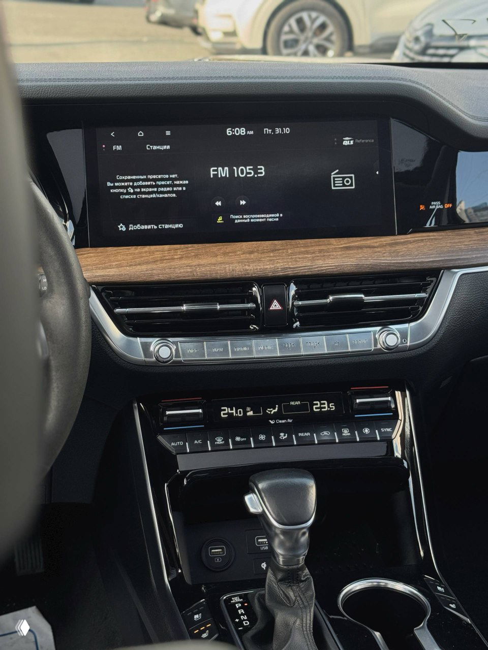 Центральная консоль салона KIA Mohave: широкоформатный дисплей мультимедиа, деревянная отделка торпедо и органы управления климатом, вид на селектор КПП.