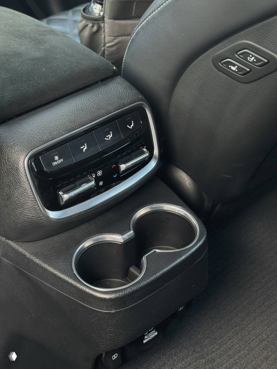 Крупный план подлокотника и климат-контроля для пассажиров второго ряда в KIA Mohave: регуляторы температуры и подстаканники.