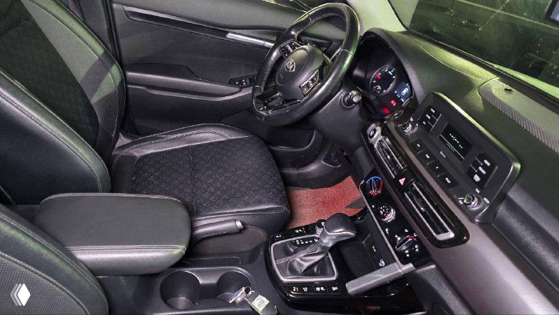 Салон KIA Seltos: вид на панель приборов, центральную консоль и рулевое колесо, фотографии интерьера с чёрной отделкой и кнопками управления.