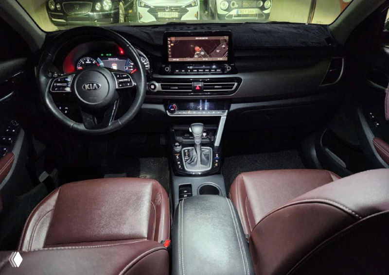 Салон другого автомобиля: панель с мультимедийным дисплеем и рычагом коробки передач, коричневая кожаная обивка передних сидений видна на фото.