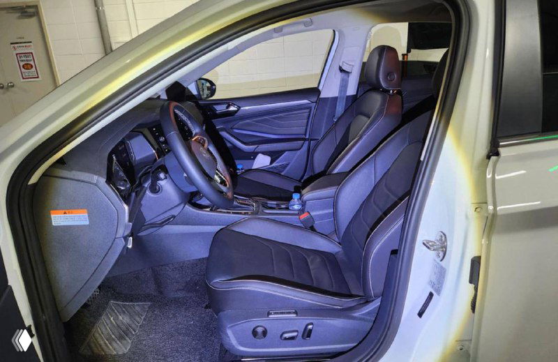 Салон Volkswagen Jetta: снимок передних сидений и рулевой колонки, видна обивка сидений и элементы управления на двери, общая компоновка салона.