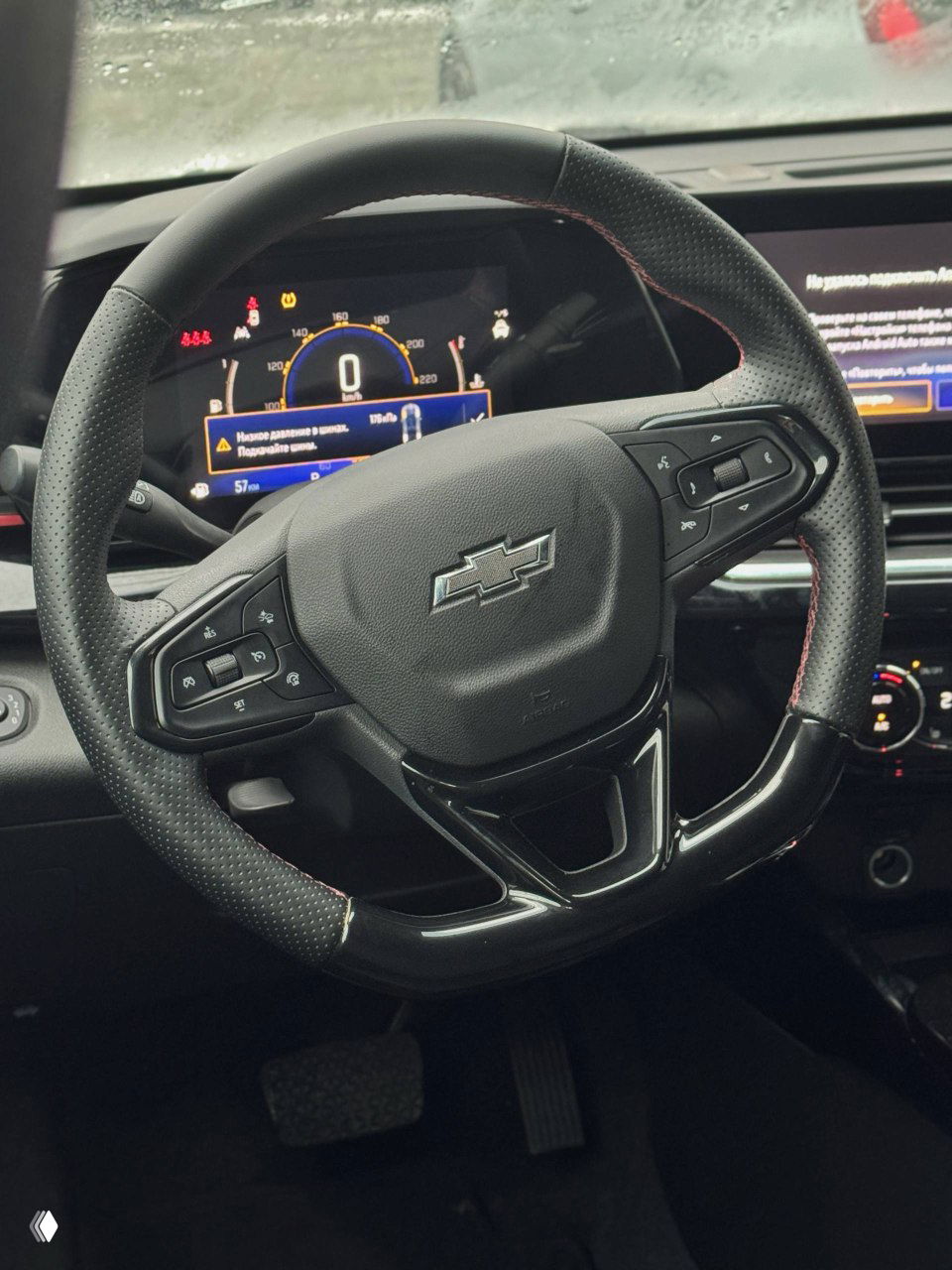 Рулевое колесо и панель приборов Chevrolet Trax, крупный план с видимым логотипом Chevrolet и элементами управления на руле