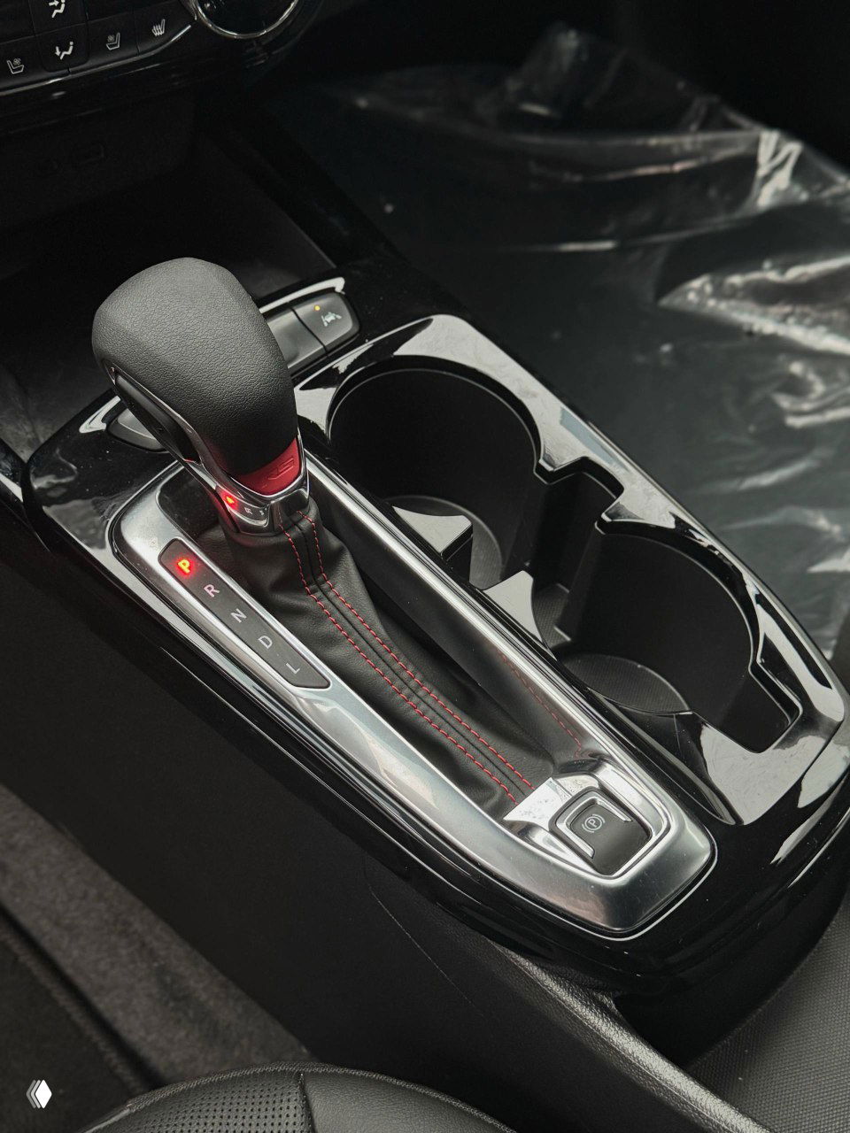 Крупный план селектора передач, подстаканников и кожаной обшивки центрального тоннеля Chevrolet Trax, видно декоративную прострочку на рычаге