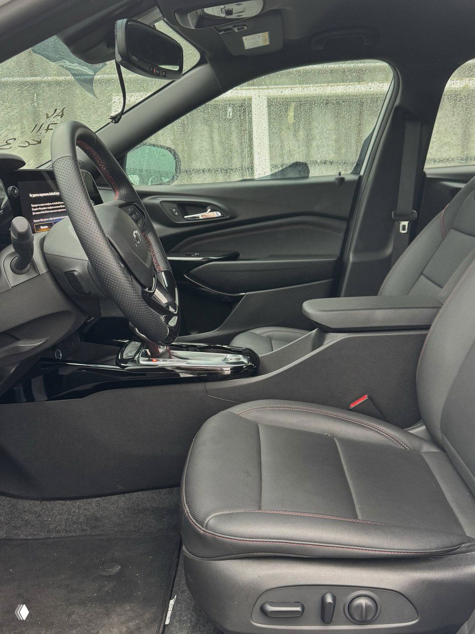 Вид на передние сиденья и центральный подлокотник Chevrolet Trax, кожаная обшивка и посадочная позиция водителя в салоне