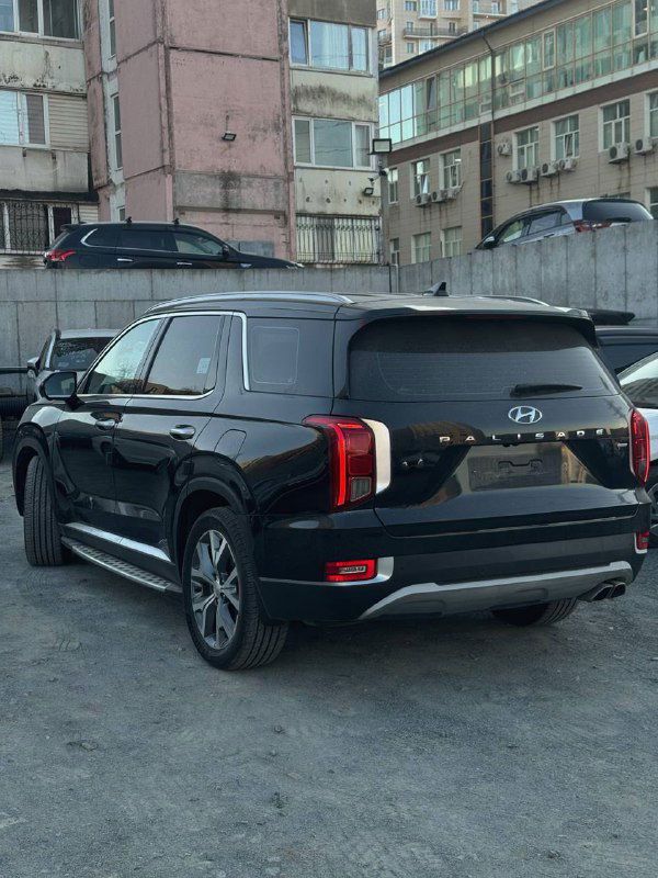 Чёрный Hyundai Palisade, вид сзади и в три четверти; заметна задняя оптика, багажник и общая габаритная форма внедорожника на городской стоянке.
