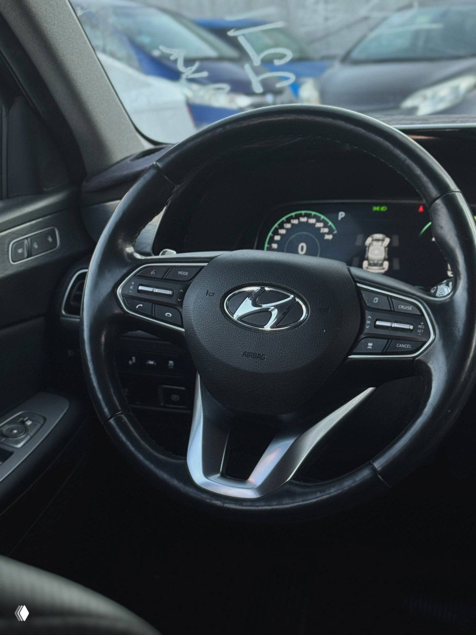 Крупный план рулевого колеса Hyundai с логотипом H на центре; вид панели приборов и мультируля, акцент на салонных элементах управления и материал обивки.