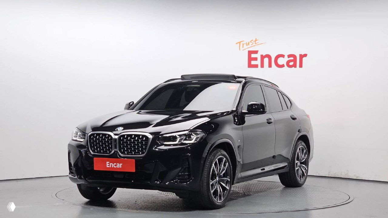 Чёрный BMW X4 xDrive 20i M‑Sport на поворотном постаменте в шоуруме Encar — передний ракурс и фирменная решётка радиатора, автомобиль в хорошем состоянии.