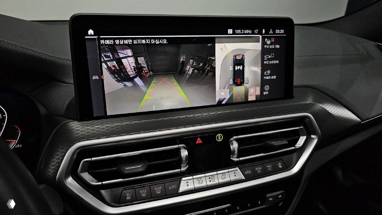 Экран мультимедиа BMW X4 показывает камеру заднего вида и панорамный обзор парковки; интерфейс на корейском языке и графика траектории движения.