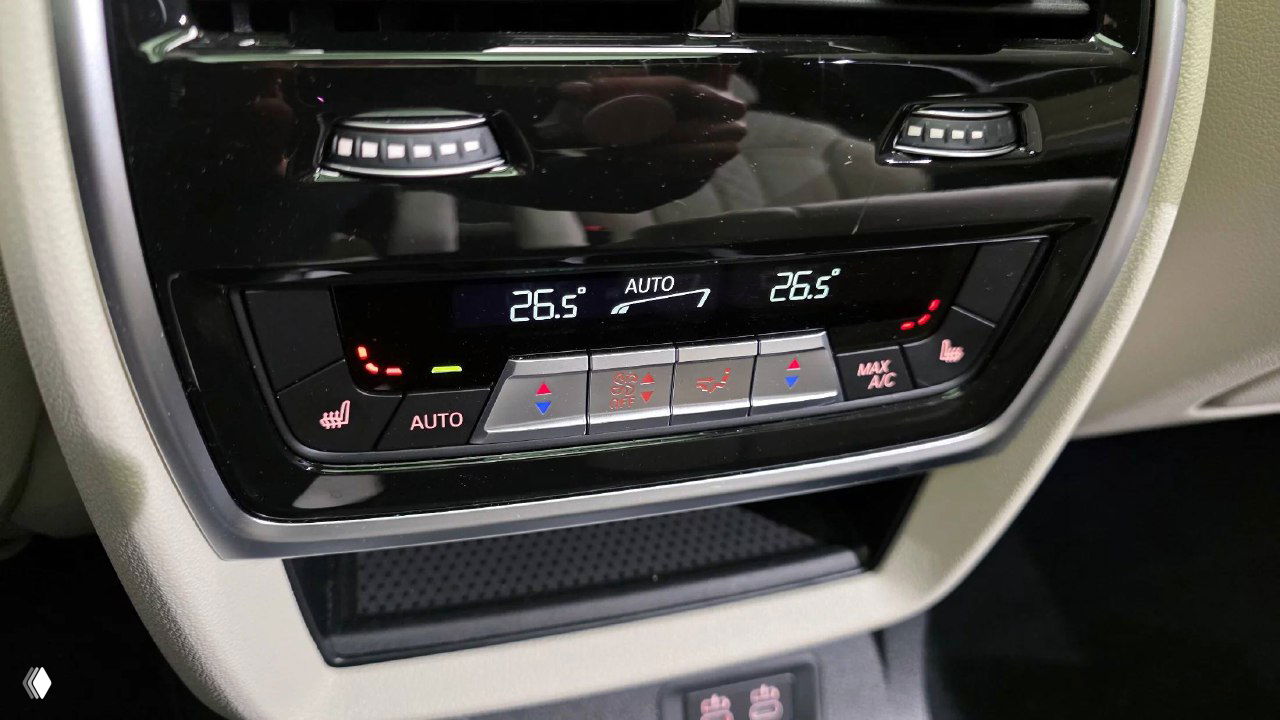 Панель климат-контроля в BMW X7: цифровые индикаторы температуры, кнопки управления климатом и подогревом сидений в зоне переднего ряда.