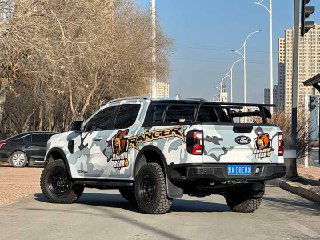 Задний ракурс Ford Ranger в камуфляжной окраске, видна грузовая платформа, багажник и защитные элементы, автомобиль на городской стоянке.