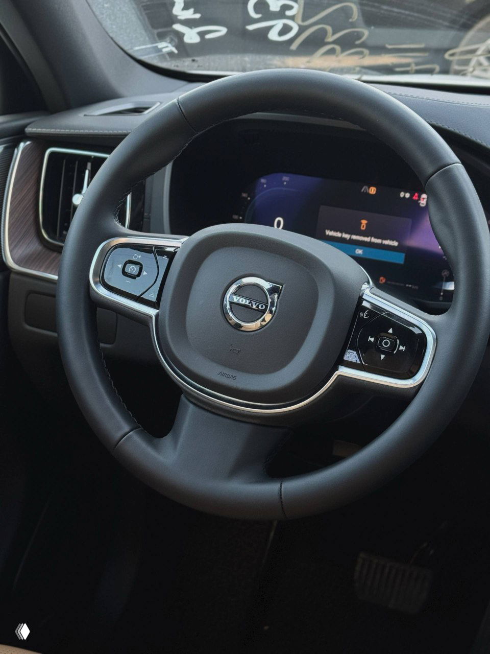 Рулевое колесо Volvo крупным планом с эмблемой, видна цифровая приборная панель и часть салона, акцент на эргономике и отделке.
