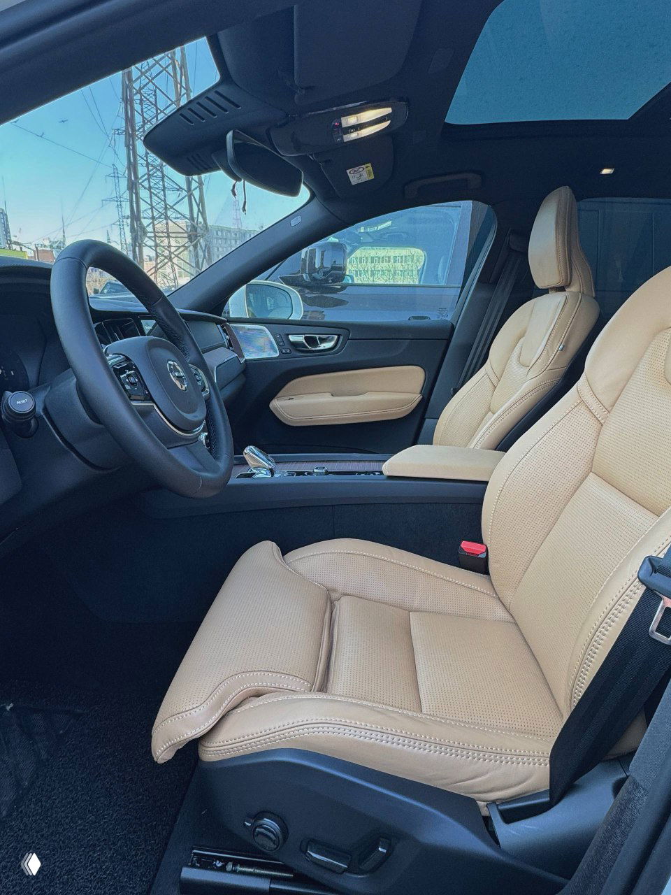 Передние бежевые кресла Volvo XC60, панорамная крыша, видно качество кожи, регулировки и общий простор салона.