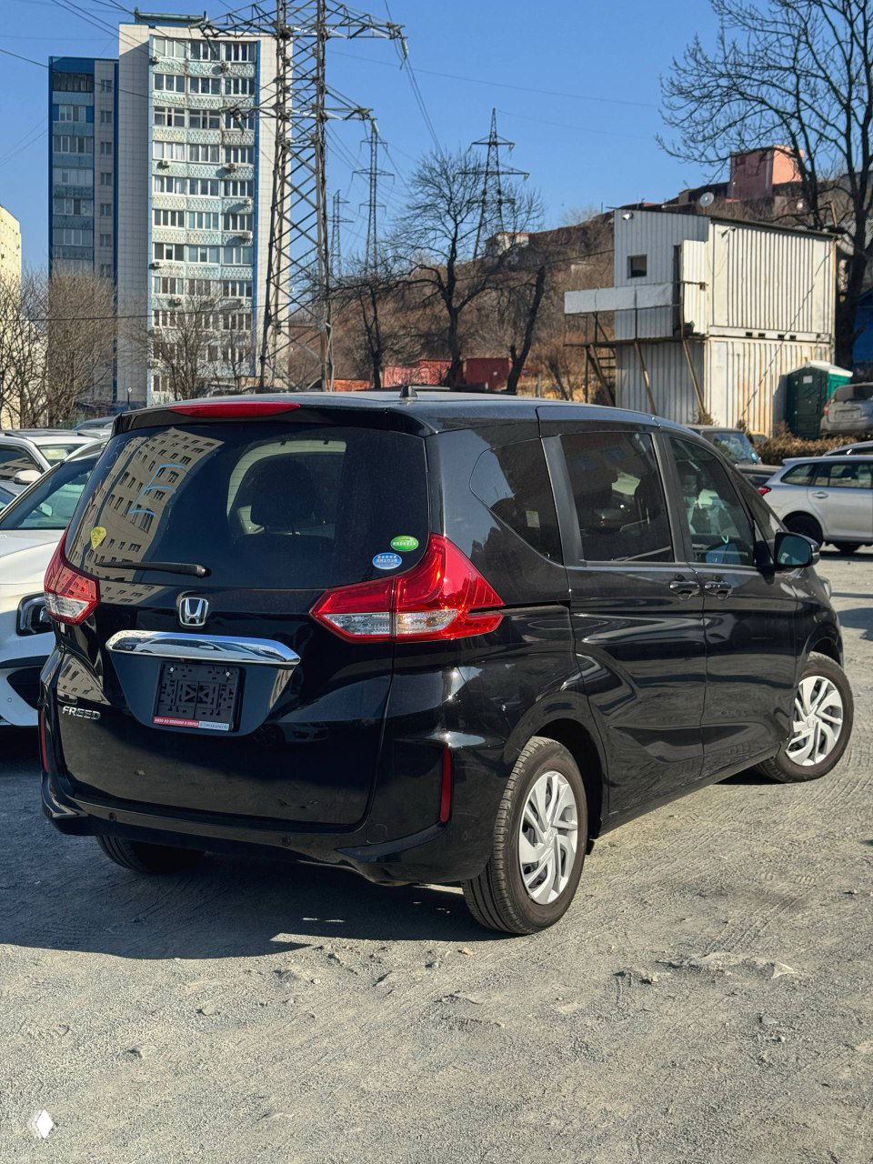 Чёрный Honda Freed 2021: задний ракурс на стоянке, видно форму фонарей и багажной двери; автомобиль подготовлен к отправке.
