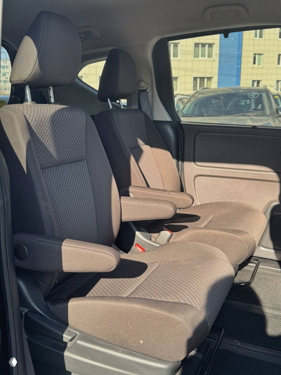 Передние пассажирские сиденья Honda Freed 2021: коричневая тканевая обивка, подлокотники и общее состояние салона отображены крупным планом.