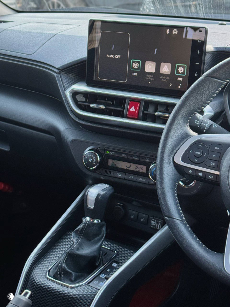 Центральная консоль и мультимедийный экран Toyota Raize, крупный план экрана, элементы управления климатом и селектор вариатора видны отчётливо.