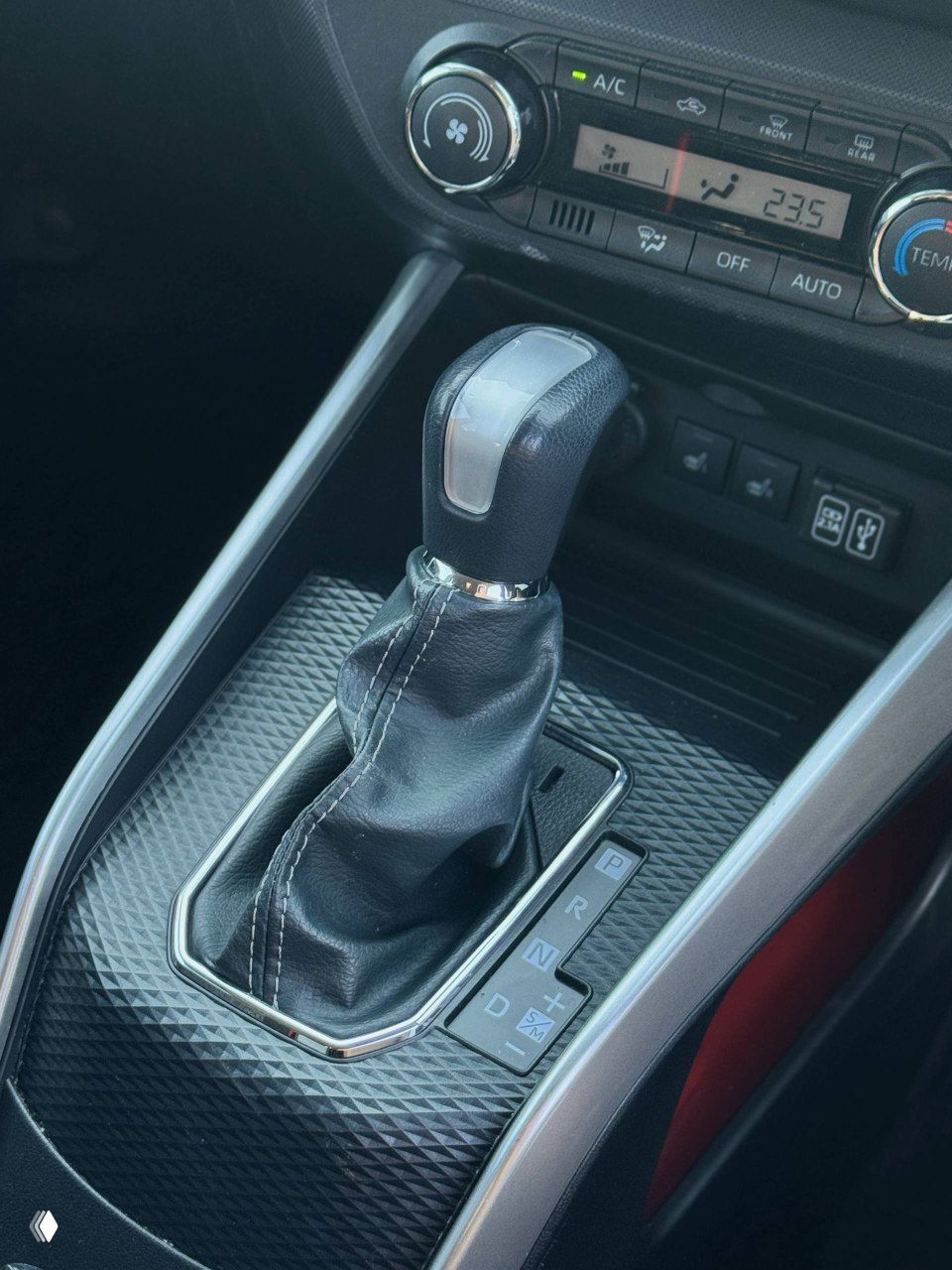 Селектор вариатора Toyota Raize крупным планом, кожух рычага КПП и окантовка центральной консоли, состояние чехла и маркировка передач.