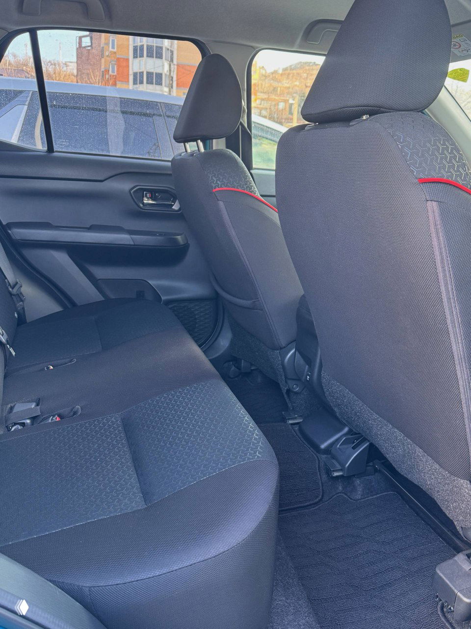Задний ряд сидений Toyota Raize — чёрная тканевая обивка, вид на пространство для ног и состояние задних сидений без пятен и повреждений.