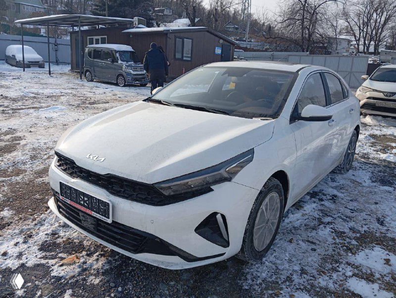 Белая KIA K3 на зимней парковке, вид три четверти, автомобиль на площадке у транспортной компании, подготовлен для отправки в регион.