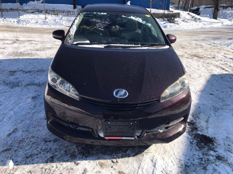 Лицевая часть Toyota Wish тёмного цвета на снежной стоянке, передний план, машина для отправки клиенту из Москвы, номера сняты.