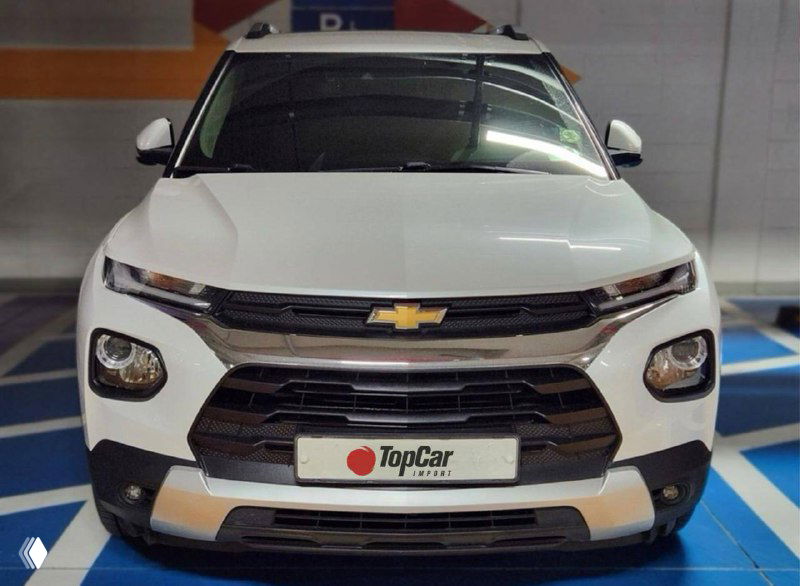 Белый Chevrolet (Trailblazer) — вид спереди в многоуровневой парковке с табличкой TopCar; фотография экстерьера лота для оценки внешнего вида.
