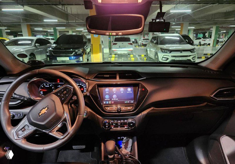 Интерьер Chevrolet: панель приборов, рулевое колесо и центральная консоль, вид из кабины на стоянку; фото состояния салона перед продажей.