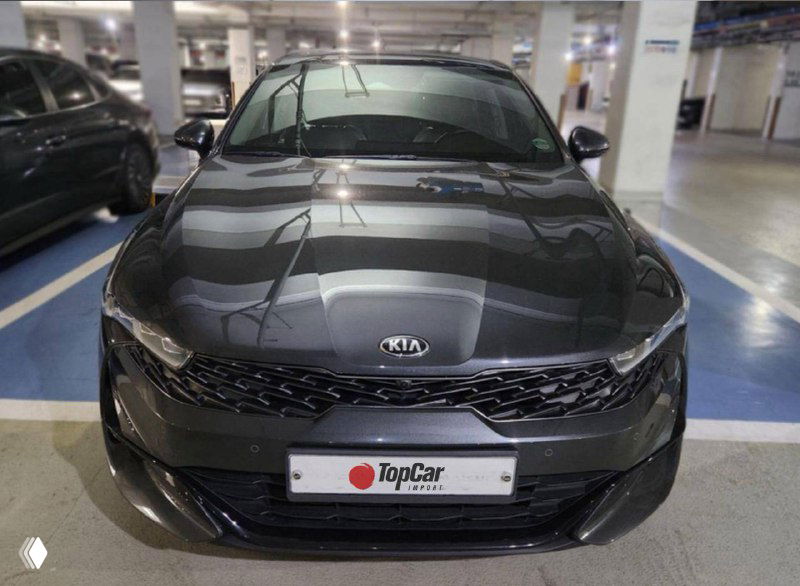 Чёрный KIA K5 — вид спереди в подземной парковке с логотипом KIA на капоте и табличкой TopCar; фото экстерьера для объявления о продаже автомобиля.