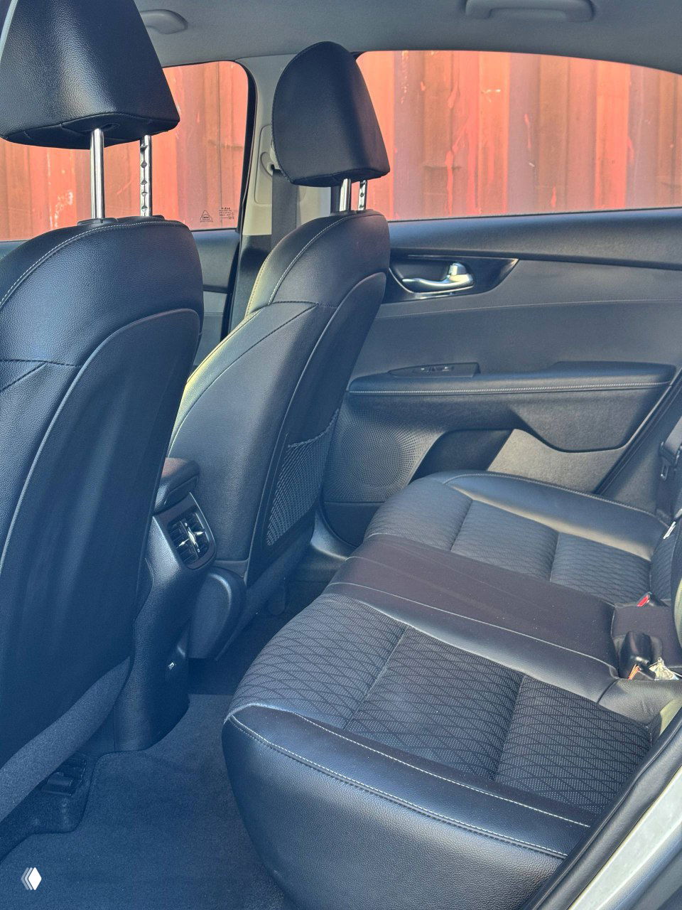 Задний ряд сидений KIA K3: простор, чёрная тканевая и кожзамённая отделка, вид на спинки и пространство для ног.