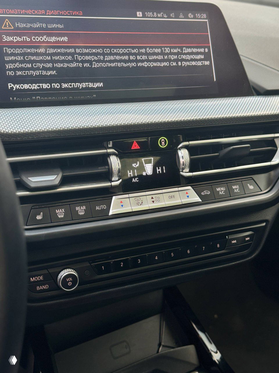 Детальный вид зоны селектора передач и подстаканников BMW, чёрная лакированная поверхность отражает фотографа, видны кнопки запуска и режимы движения.