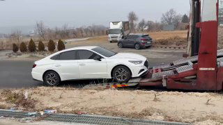 Белый седан KIA K5 на погрузочной рампе автовоза, крупный план процесса загрузки для отправки во Владивосток.