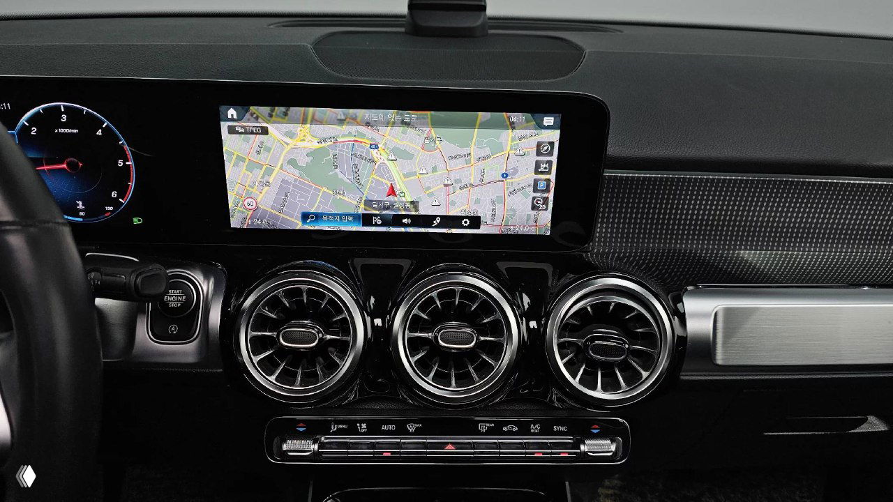 Крупный план центральной консоли Mercedes GLB200d с навигационной картой на дисплее и тремя круглыми вентиляционными соплами, отделка торпеды.