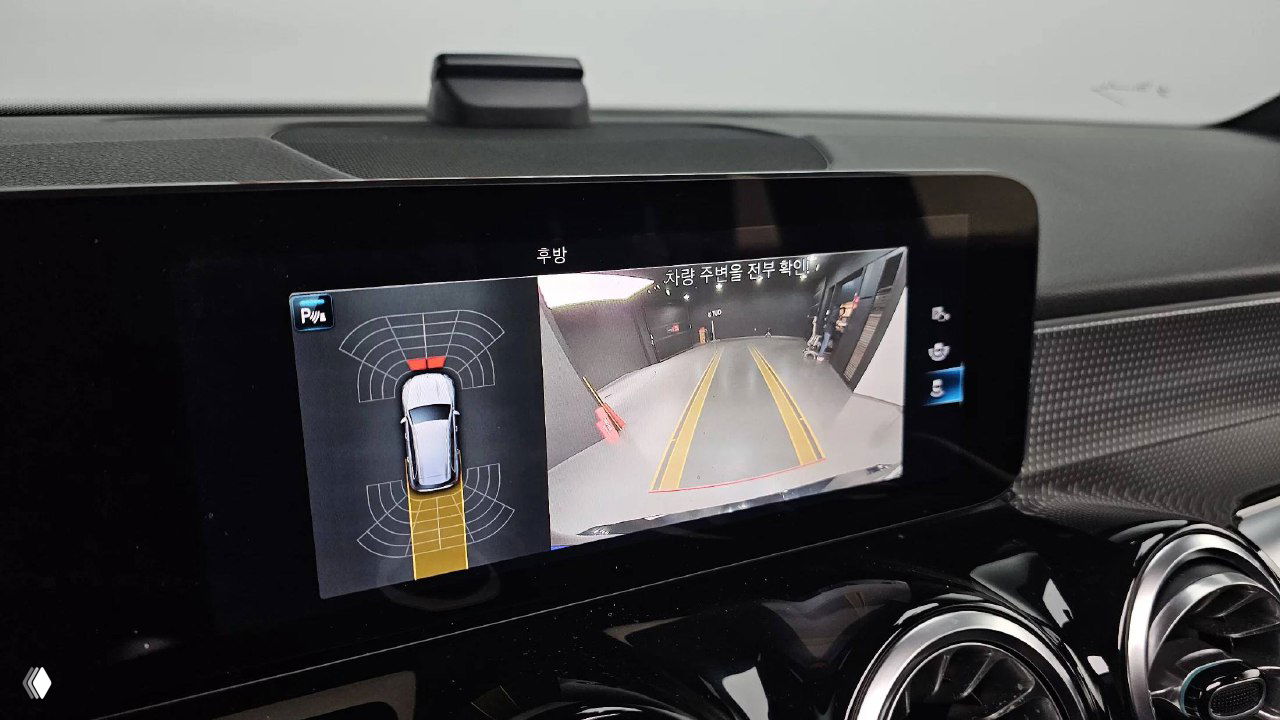 Дисплей камер и парктроника Mercedes GLB200d в режиме парковки, показаны зоны обнаружения и обзор задней части автомобиля на экране.