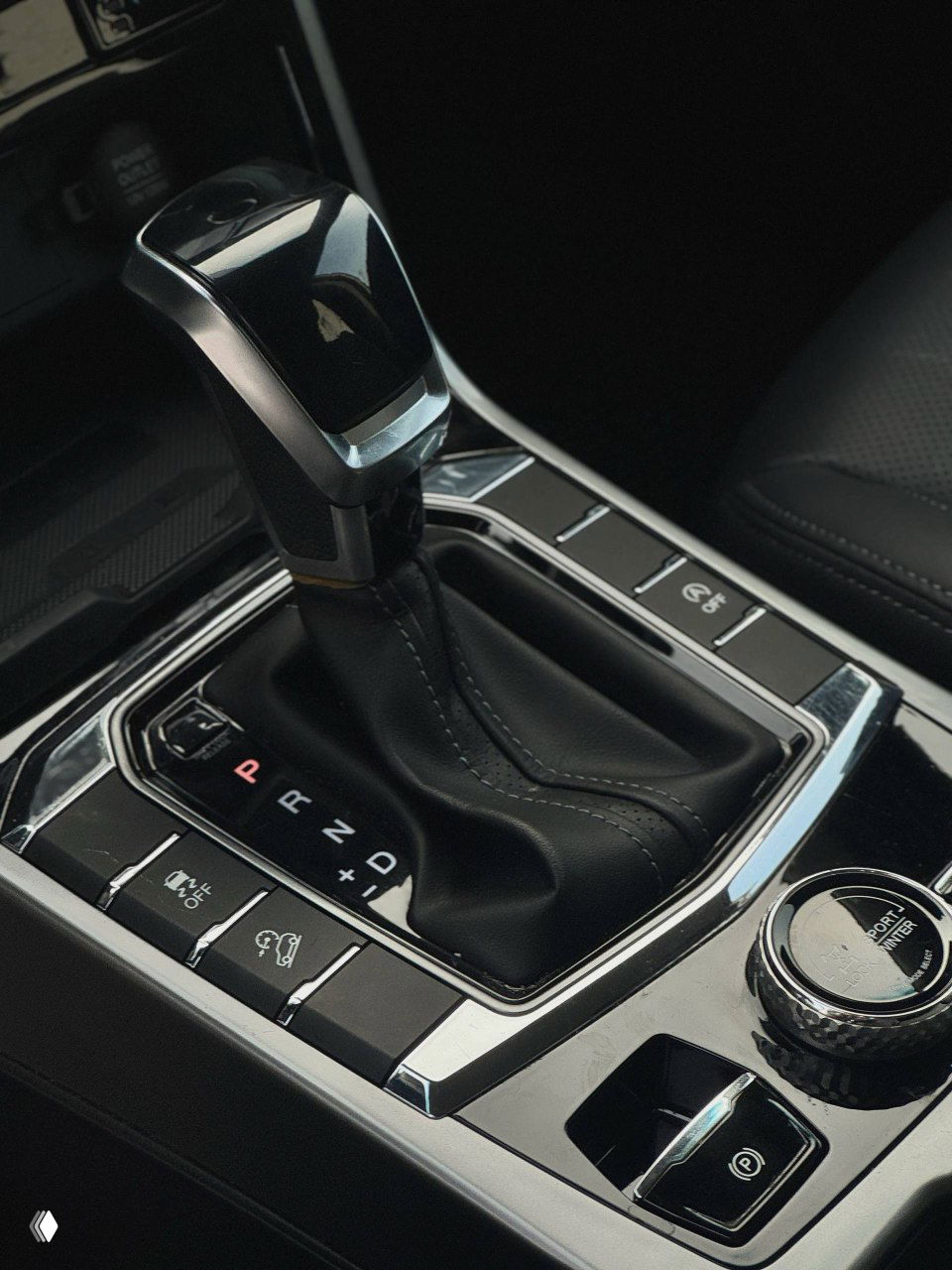 Крупный план рычага автоматической коробки передач и селектора режимов движения в центральном тоннеле белого SsangYong Korando, хромированные вставки.