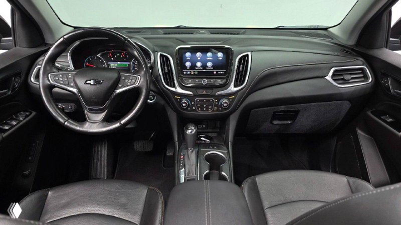 Вид салона Chevrolet Equinox: передняя панель и центральная консоль с мультимедийным экраном, чёрная отделка сидений и детали интерьера.