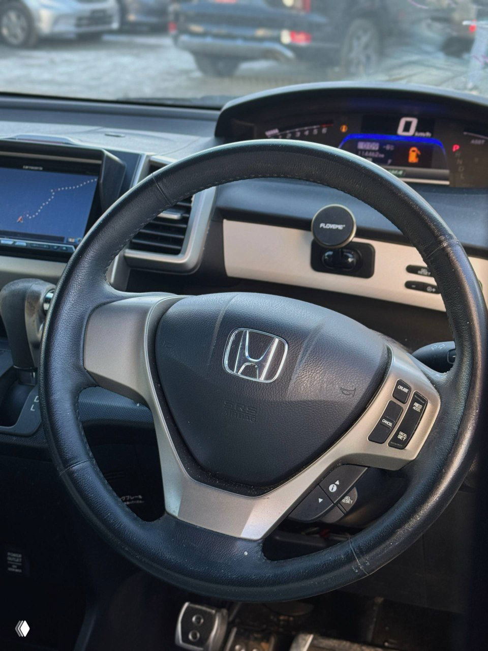 Салон Honda Freed: вид на руль с логотипом Honda, центральную приборную панель и цифровой спидометр, руль с элементами управления.