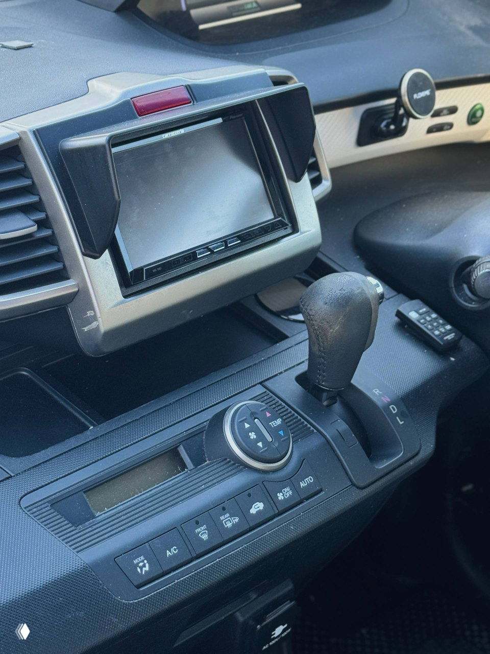 Интерьер Honda Freed: центральный дисплей мультимедиа и область вокруг рычага передач, вид на управление развлекательной системой.