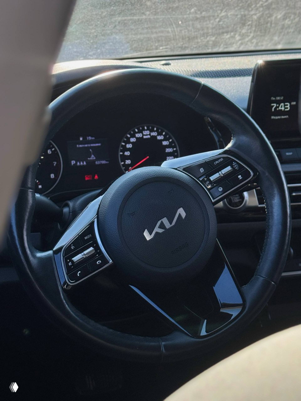 Руль KIA с логотипом, вид с водительского места, крупный план панели управления и приборов, салон автомобиля в фокусе