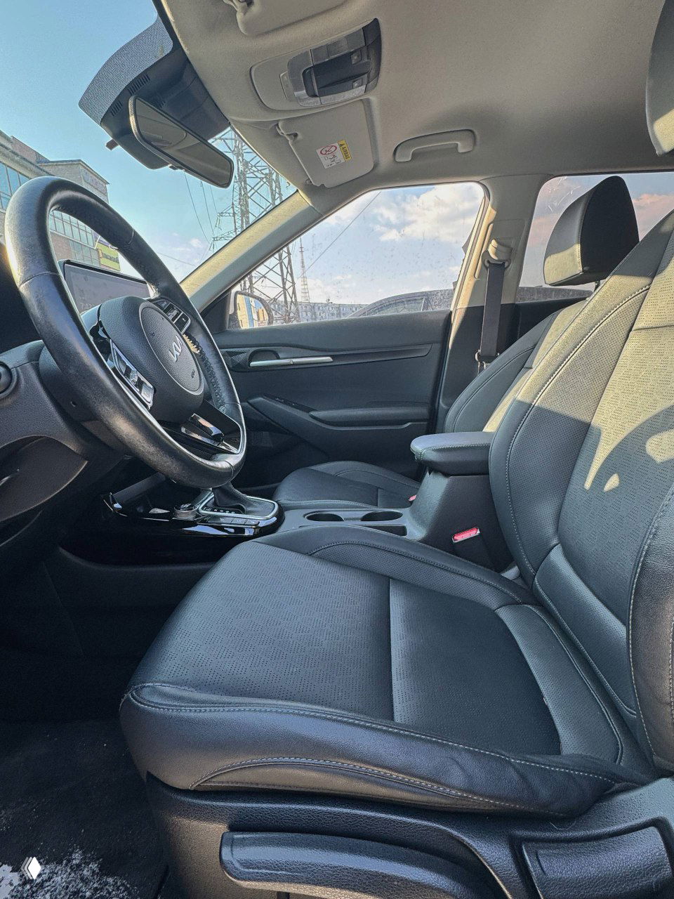 Передние сиденья и центральный подлокотник KIA Seltos, салон с тканевой обивкой и видом на руль и пространство для вещей