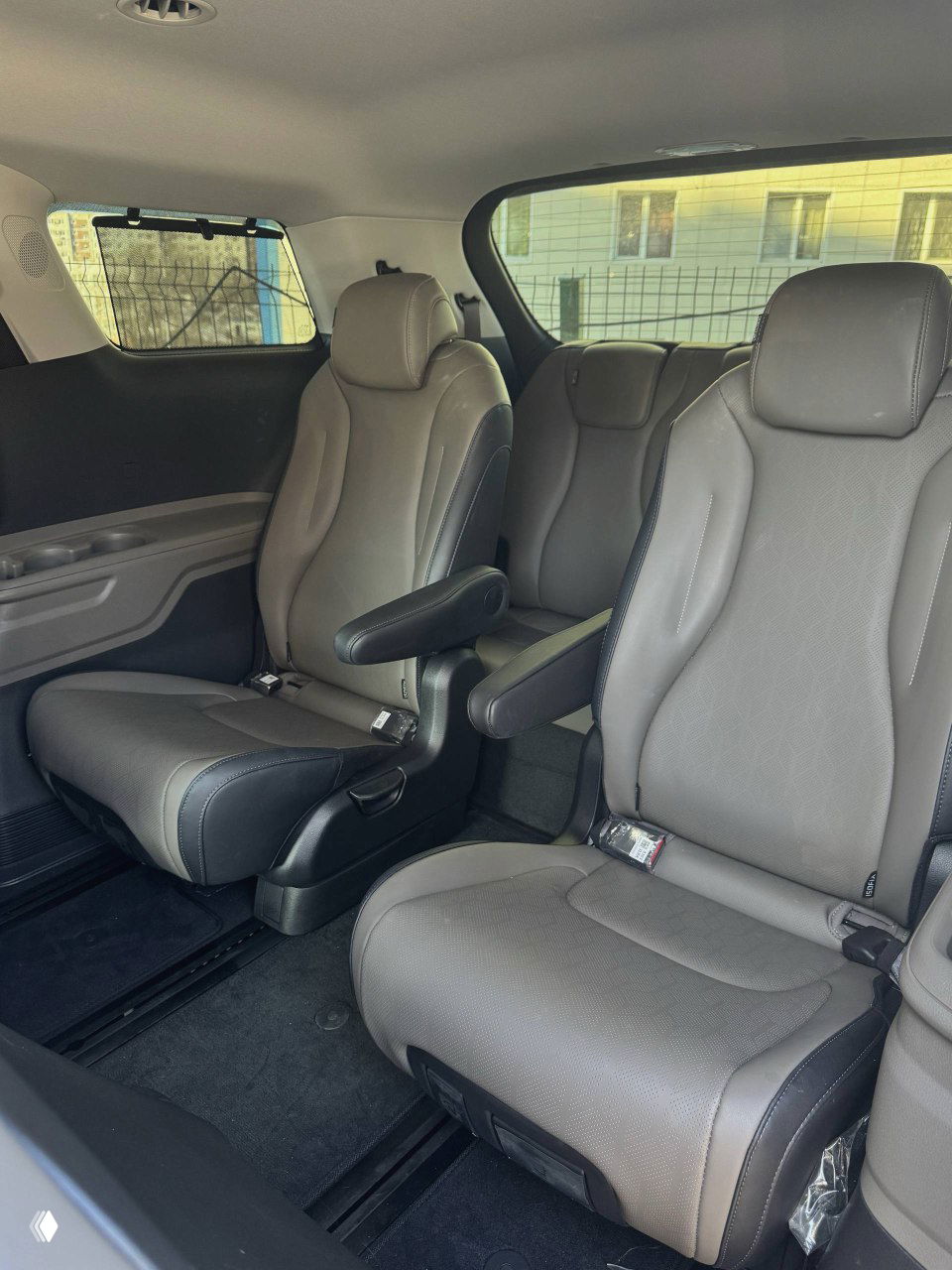 Третий ряд сидений и часть багажного отсека KIA Carnival, вид на задние сиденья с просторным салоном и детальными швами обивки.