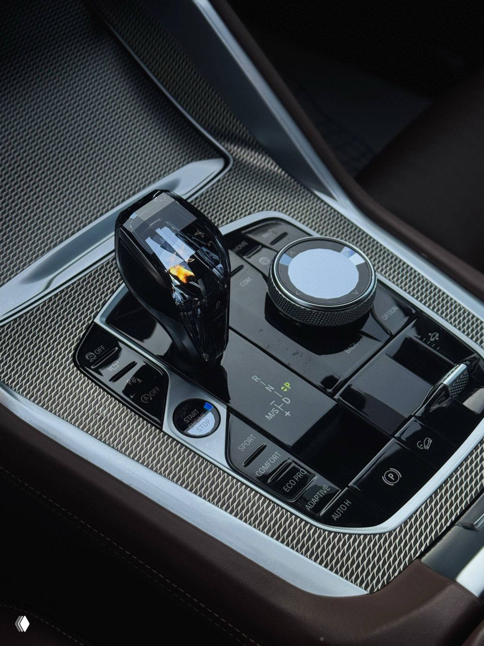Крупный план центрального тоннеля и селектора передач BMW X6: стеклянная ручка селектора, контроллер iDrive и кнопки режимов движения.