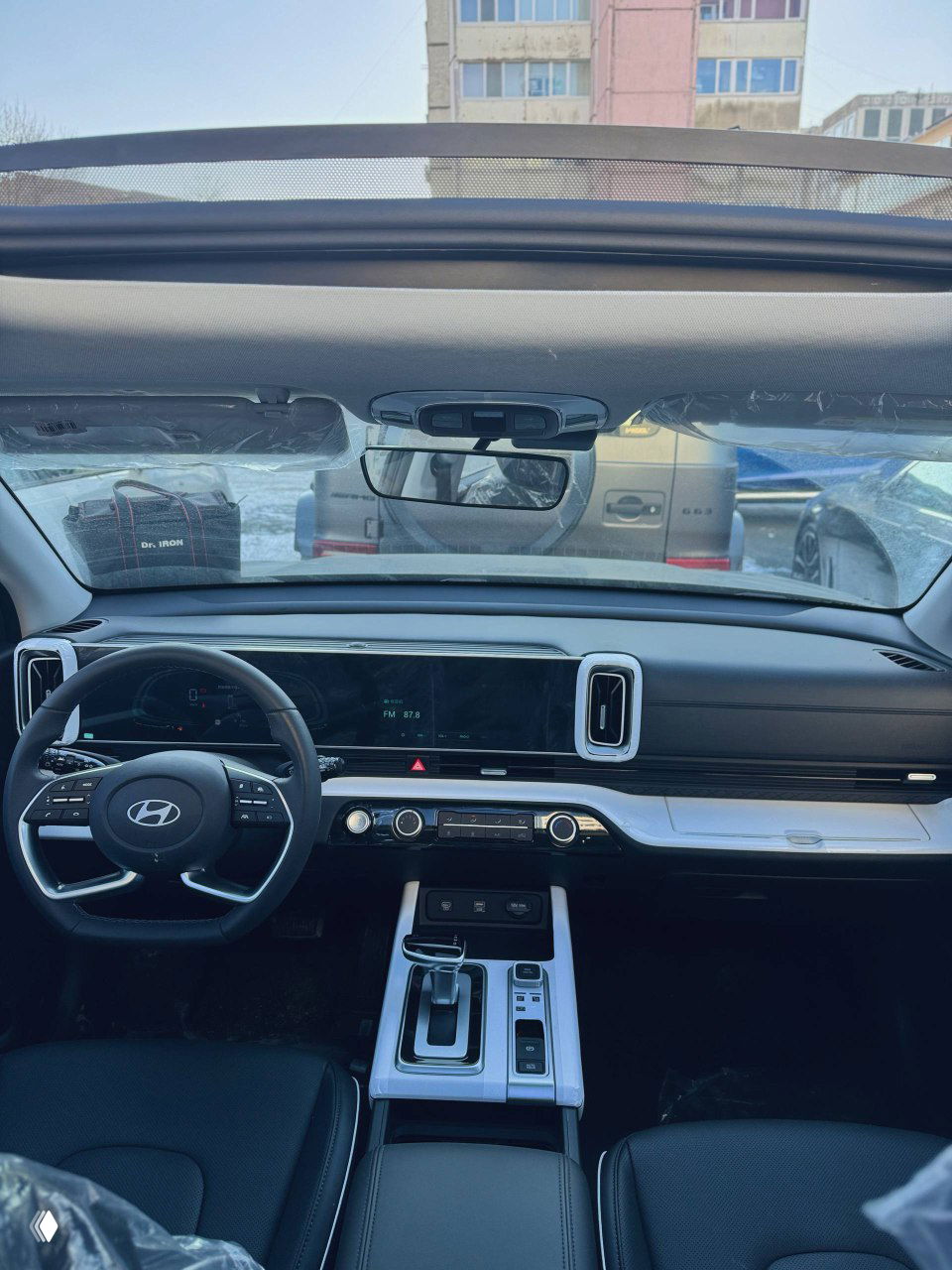 Вид на переднюю панель и ветровое стекло Hyundai Mufasa — широкая цифровая приборная панель, экран мультимедиа и обзор через лобовое стекло.