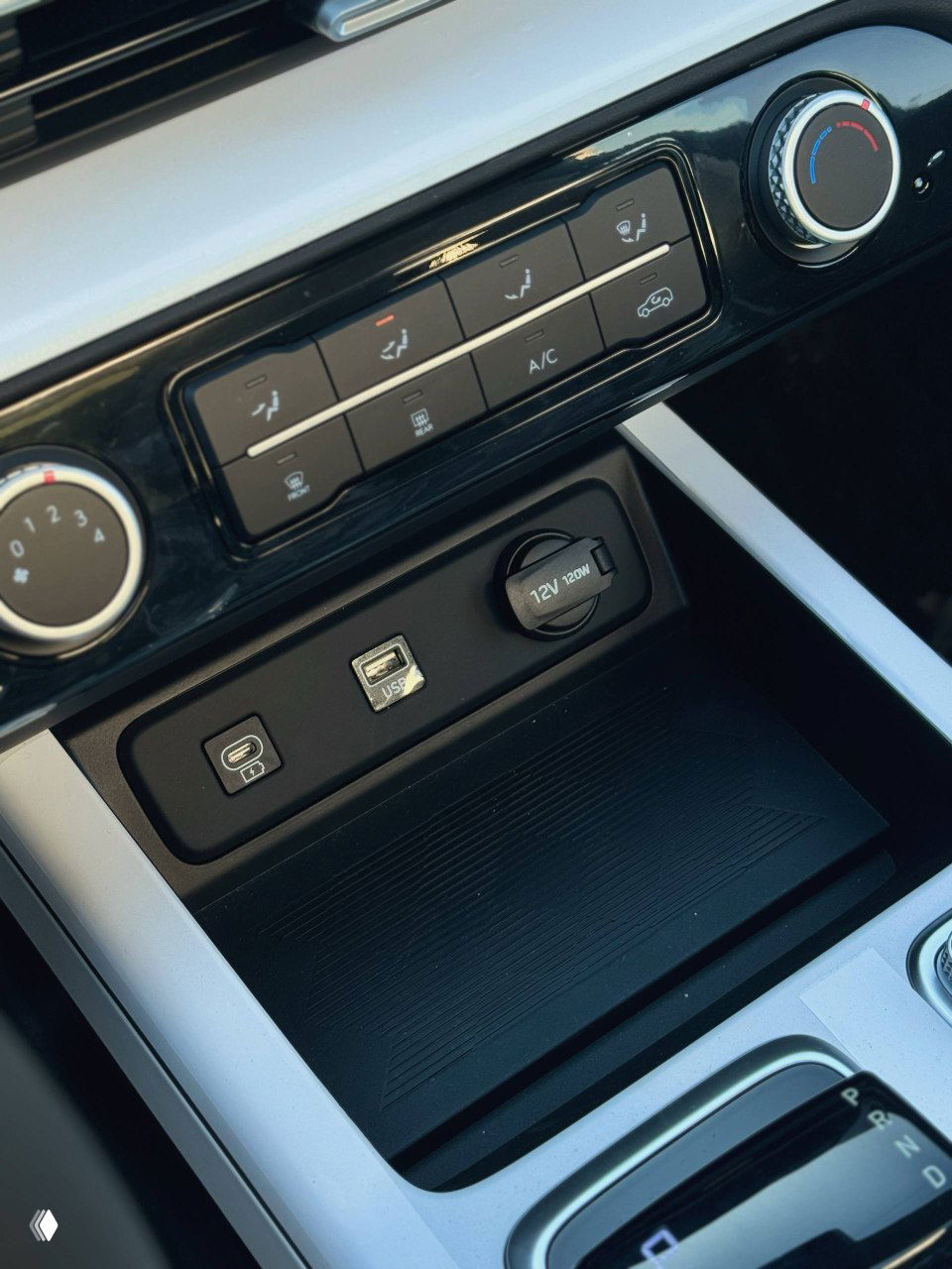 Блок разъёмов и ниша для хранения в центральной консоли Hyundai Mufasa — USB, 12V и пространство для мелких вещей на фоне декоративных элементов.