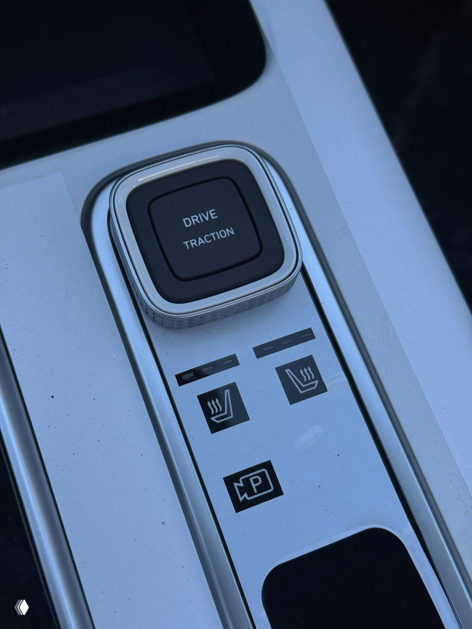 Панель с кнопкой изменения режимов движения, иконками подогрева сидений и парковочного ассистента на центральной консоли Hyundai Mufasa, крупный план.