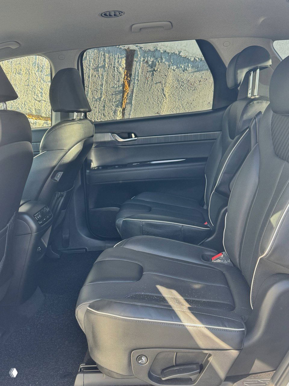 Второй ряд сидений Hyundai Palisade с чёрной обивкой, показано пространство для пассажиров и складывающиеся кресла
