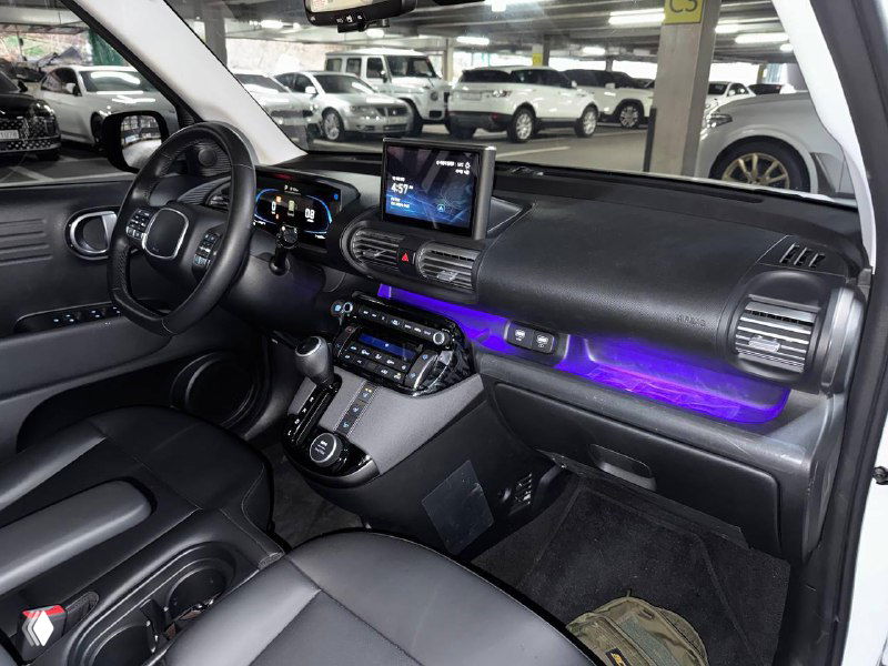 Интерьер Hyundai Casper с подсветкой приборной панели фиолетового цвета, центральный экран и мультимедийная консоль, чёрные сиденья.