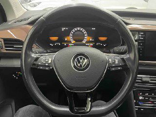 Крупный план рулевого колеса Volkswagen с эмблемой, приборной панели и кнопок управления на стойке водителя в Tharu.