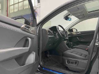 Открытая водительская дверь Volkswagen Tharu с видом на порог, сиденье и панель двери — кадр из автосалона с акцентом на комфорт.