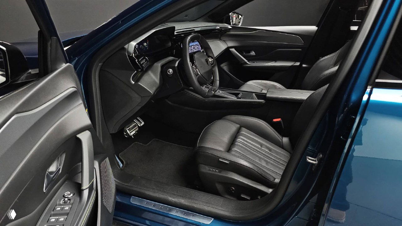 Вид водительской двери и переднего посадочного места Peugeot 408 с открытой дверью, показаны порог, регулировки сиденья и общая чистота салона.