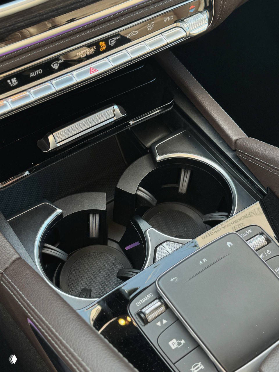 Крупный план подстаканников и отделки центральной консоли Mercedes GLE300d: хромированные детали и кожаная отделка в зоне управления.