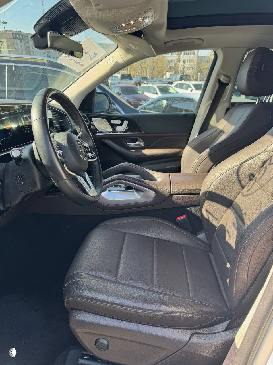 Вид на передние сиденья Mercedes GLE300d: кожа, комфортные подушки, водительское место и панорамная крыша, снимок сделан на стоянке для демонстрации состояния.